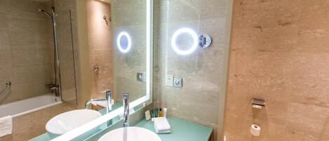 A modern bathroom with two sinks, a large mirror, and a bathtub.