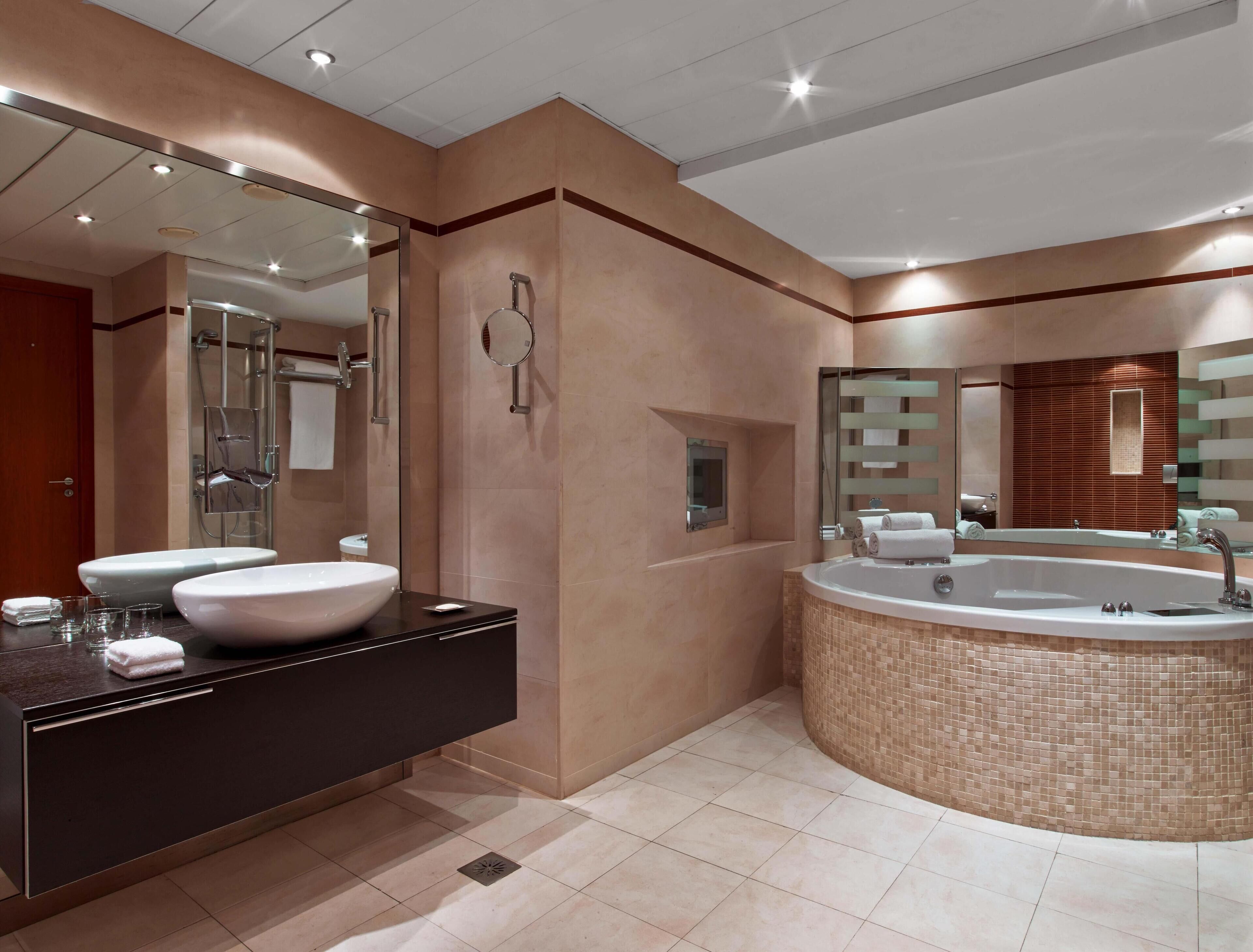 Een moderne badkamer met een grote spiegel, twee wastafels, een badkuip en een douche.