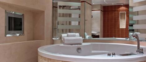 Un baño moderno con una bañera independiente grande, un espejo y un revestimiento de pared de madera.