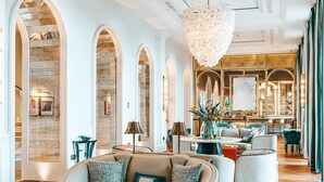 A spacious lobby with a modern chandelier, comfortable seating, and a view of the bar area.