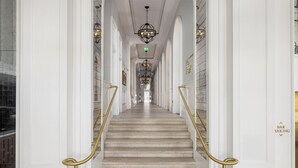 A grand hallway with marble stairs, white walls, and gold railings leading to a door marked 'BAR PARKING'.