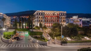 A hotel with a grand entrance, a parking area, and a view of the cityscape.