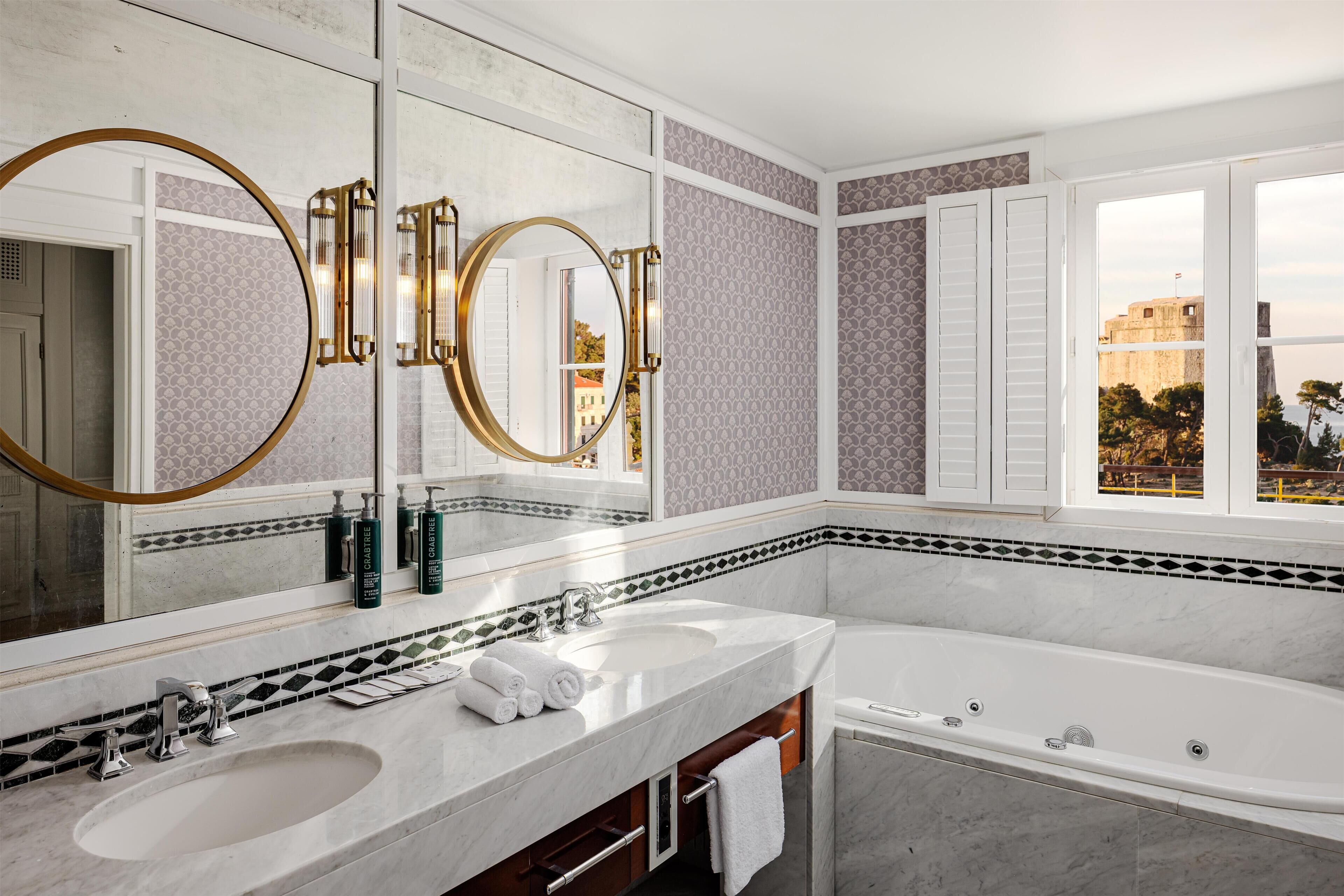 Un baño moderno con dos lavamanos, un espejo grande y una bañera.