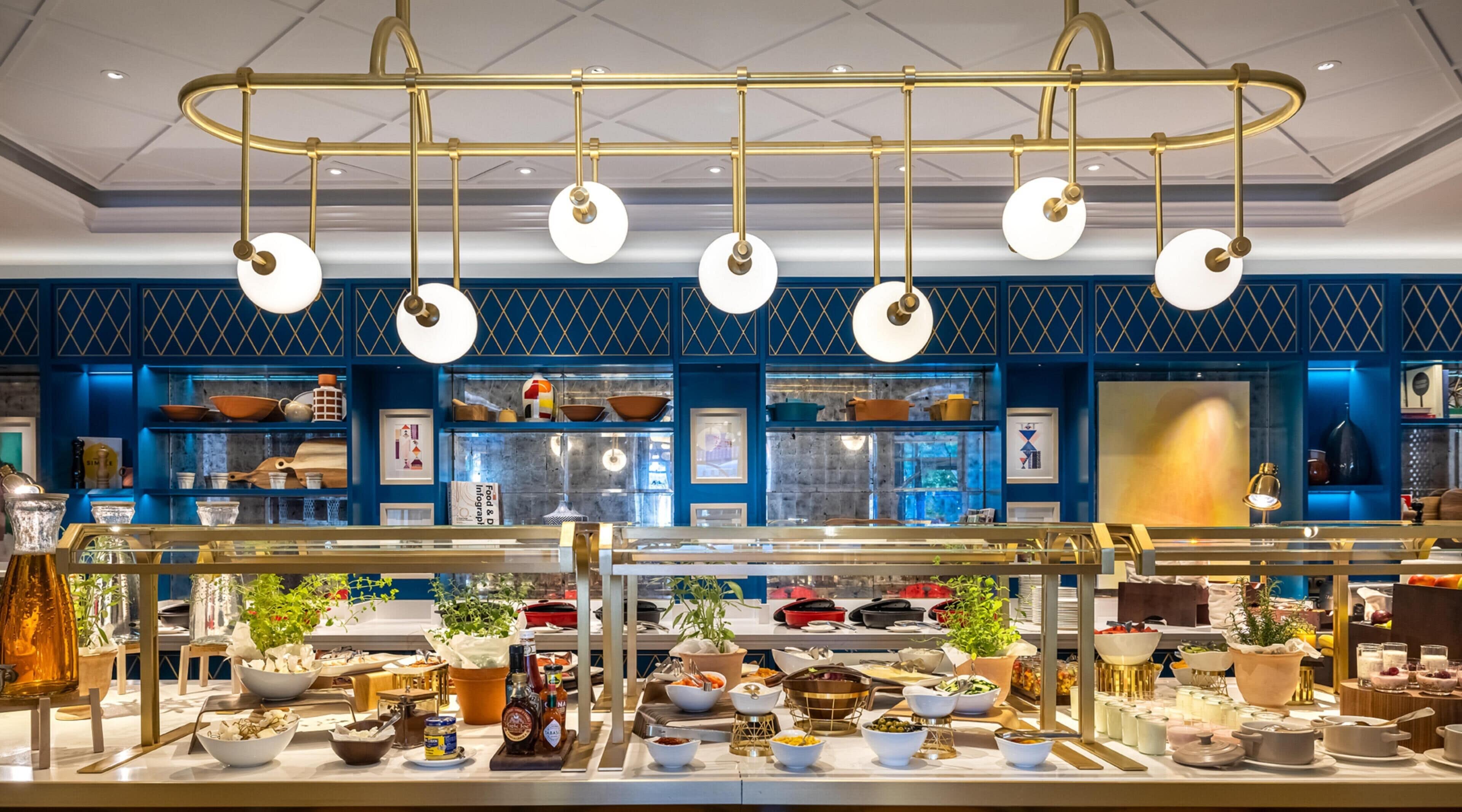 Disposição de buffet com diversos alimentos e um lustre decorativo.