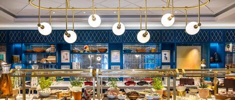 A buffet setup with various food items and a decorative ceiling light fixture.