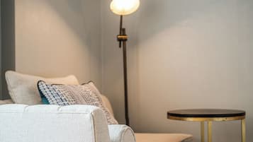 Um quarto com sofá, uma mesinha redonda e um abajur.