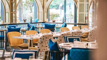 Um restaurante com mesas e cadeiras redondas, grandes janelas e vista para o exterior.