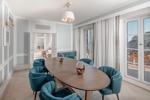 Comedor con una gran mesa ovalada, seis sillas color turquesa, un frutero y un candelabro moderno.