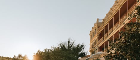 A building with a balcony and a sunlit sky.
