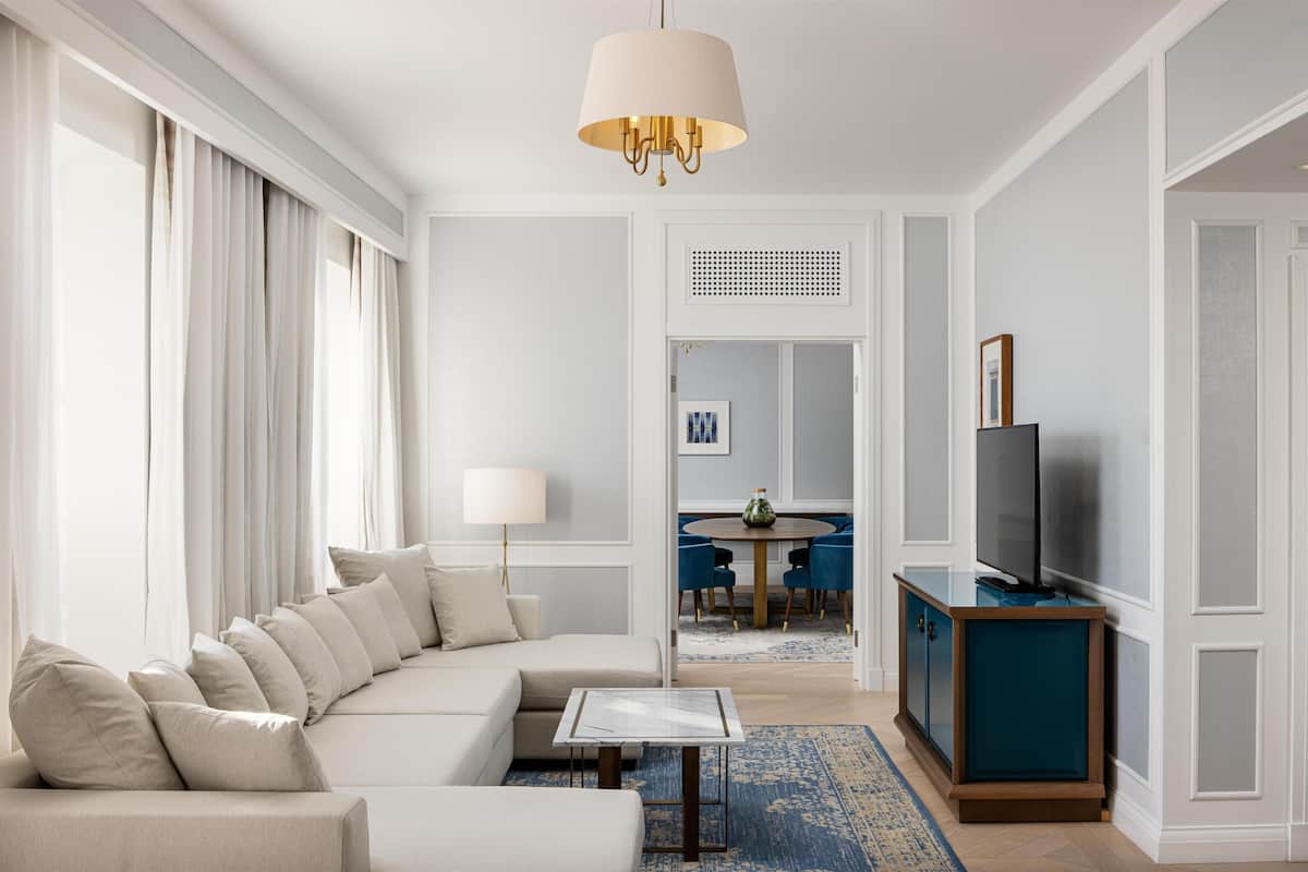 Een woonkamer met een bank, een salontafel, een tv op een meubel en een eethoek op de achtergrond.
