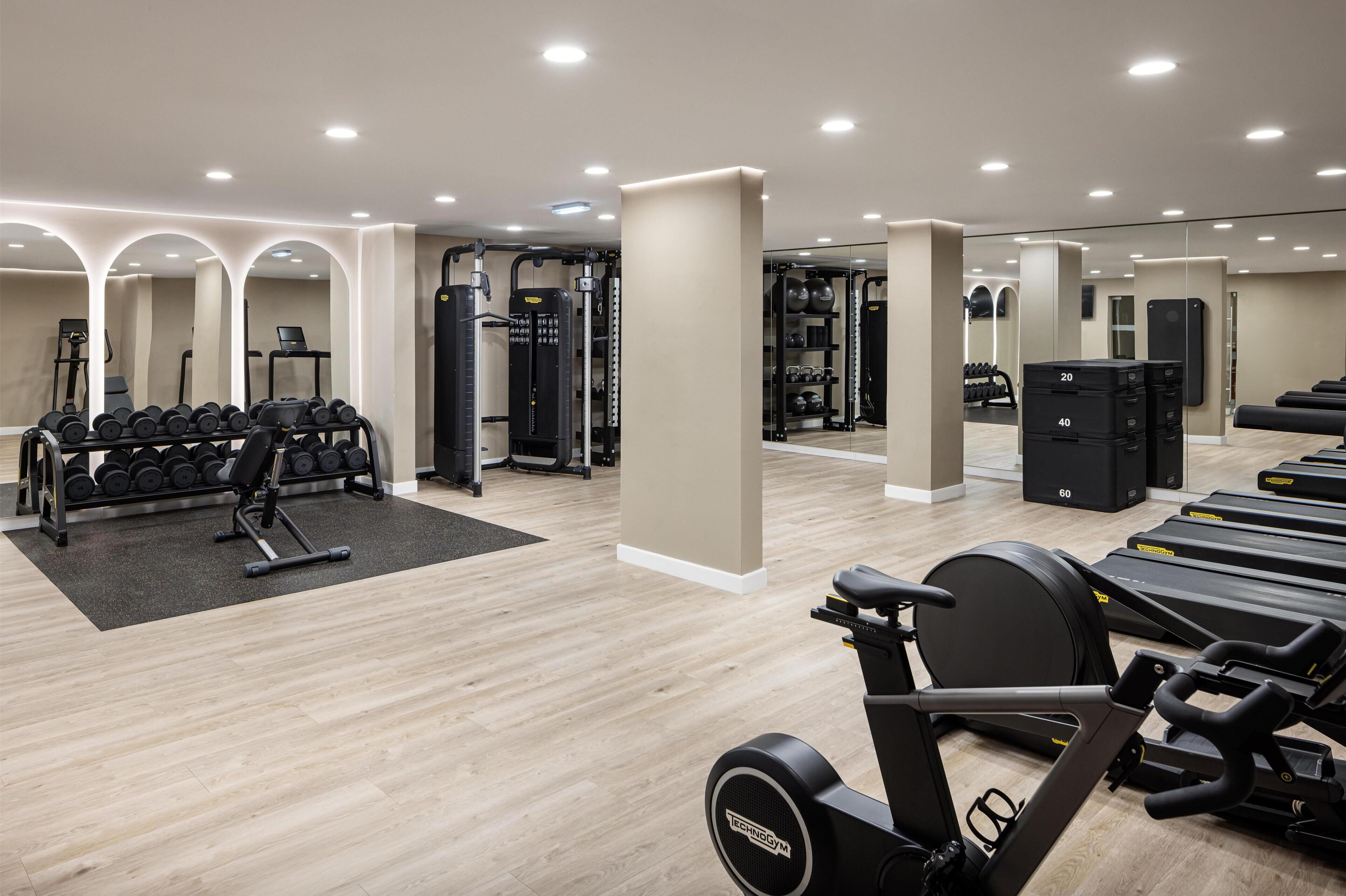A gym with treadmills, dumbbells, and weight machines.