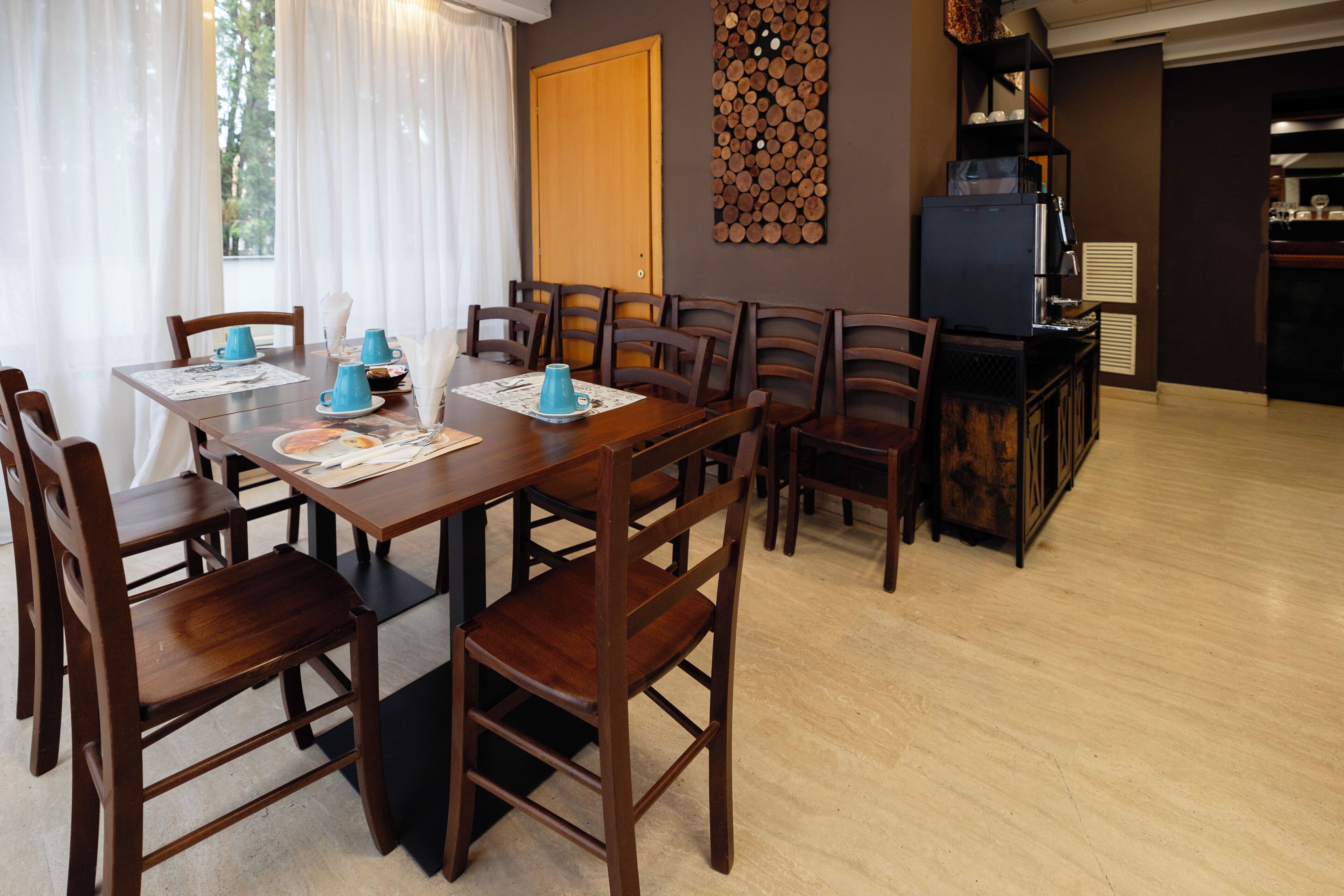 Een eethoek met een houten tafel en stoelen, een koffieapparaat en een decoratief wandobject.