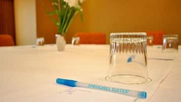 A table with a clear glass tumbler, a pen, and a vase with flowers.