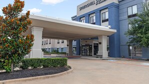 L’entrée d’un hôtel, avec un passage couvert, une enseigne indiquant « Springhill Suites by Marriott » et un espace de stationnement.