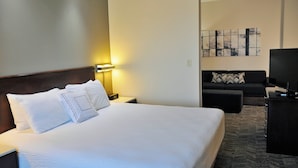 Une chambre d’hôtel avec un grand lit, une table de chevet avec une lampe, un canapé et un téléviseur.