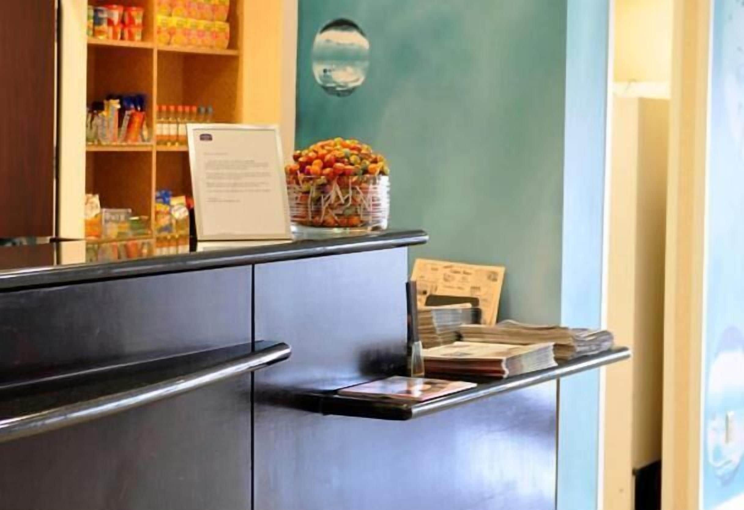 A reception desk with a menu, a fruit basket, and a wall-mounted mirror.