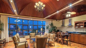 A spacious living area with a large window, a dining table, and comfortable seating. - Hotel Casa Roland San José (San José)