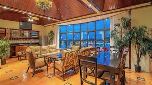 A spacious room with a large dining table, comfortable seating, a kitchen area, and a view of a pool. - Hotel Casa Roland San José (San José)