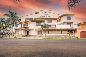 Un hotel moderno llamado La Junta con una entrada destacada y un cartel que indica que es Casa Roland.