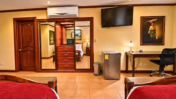 A hotel room with a bed, a desk, a chair, a television, and a trash can.