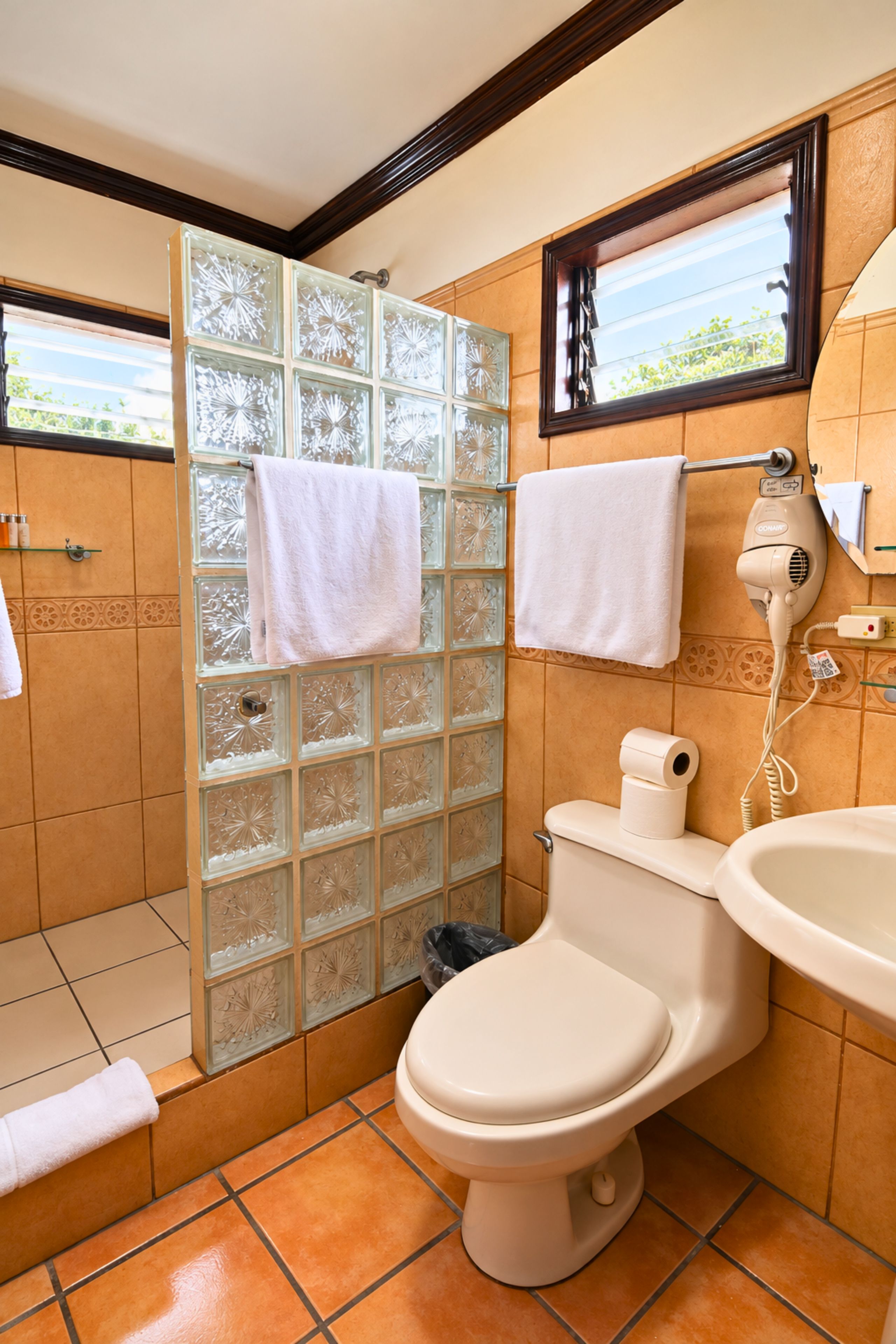 Un baño con inodoro, lavamanos y ducha con paneles de vidrio.
