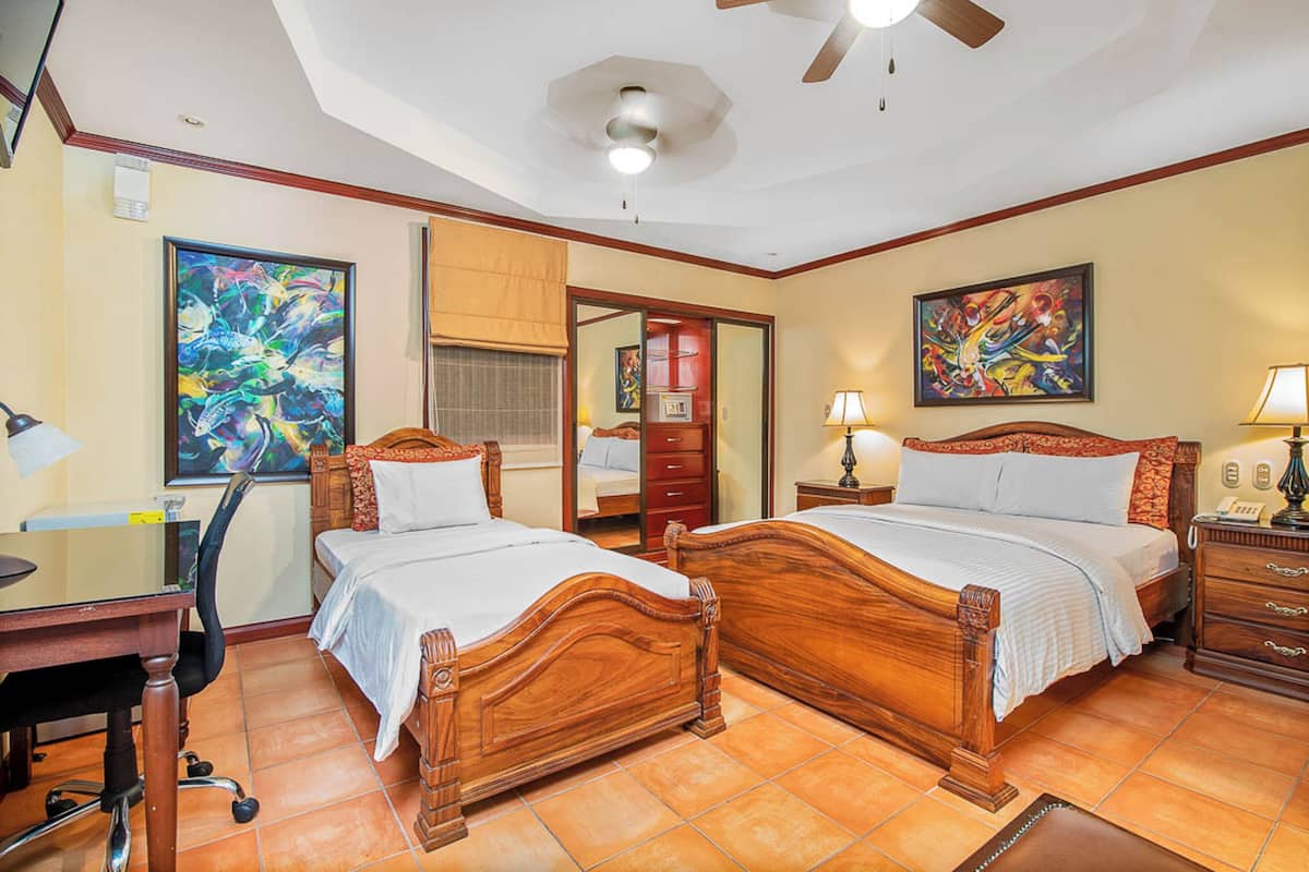 A hotel room with two wooden beds, a desk, and a chair.