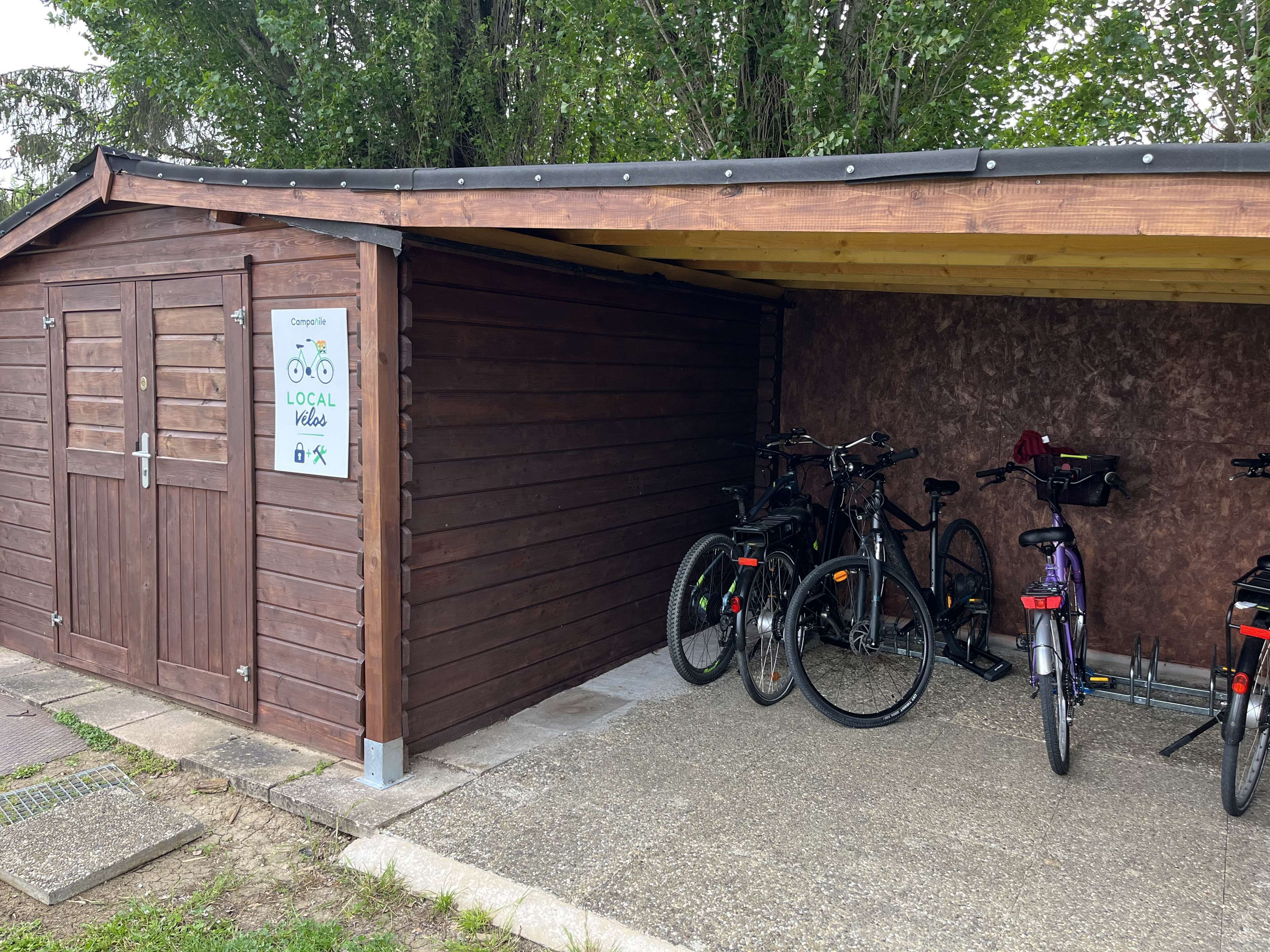Un bâtiment en bois avec une porte de garage, une enseigne et des vélos garés à l’intérieur.