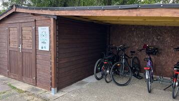 Un edificio de madera con puerta de garaje, letrero y bicicletas estacionadas dentro.