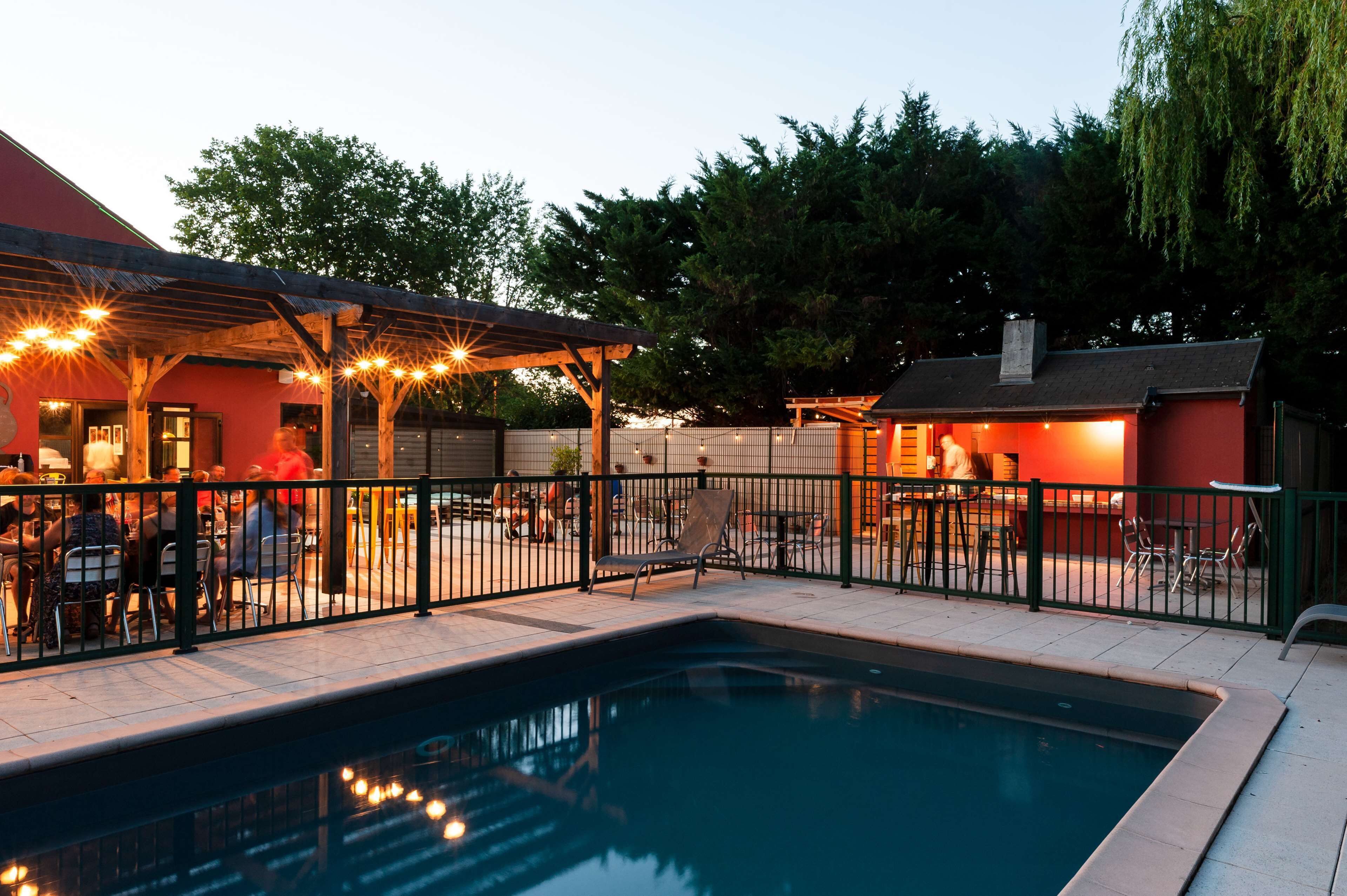 A pool area with a covered patio, outdoor seating, and a fenced enclosure.
