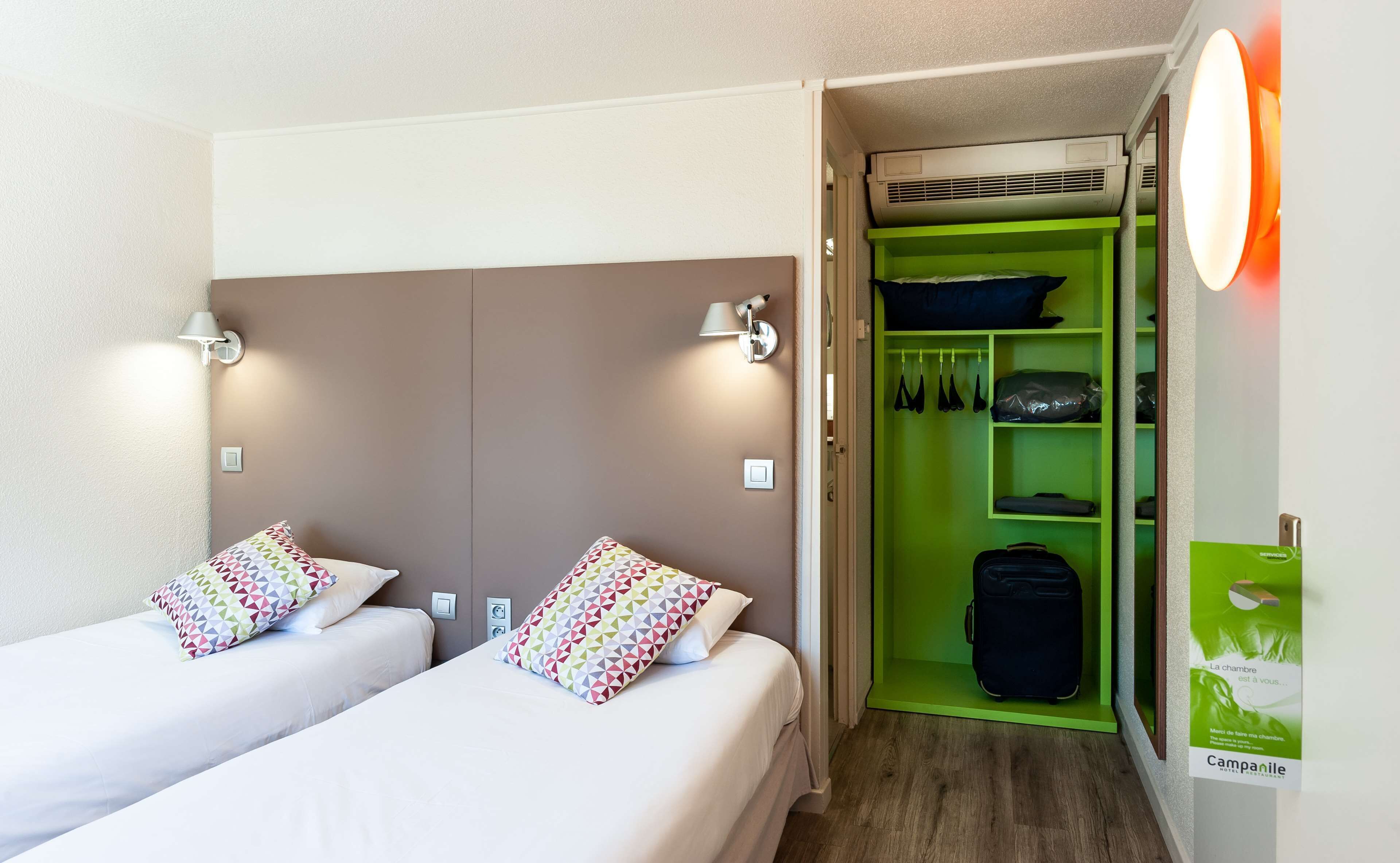 Ein Hotelzimmer mit zwei Betten, einem grünen Schrank und einem Bild an der Wand.