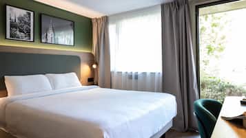 Une chambre d’hôtel avec un lit, un bureau et une fenêtre avec des rideaux.