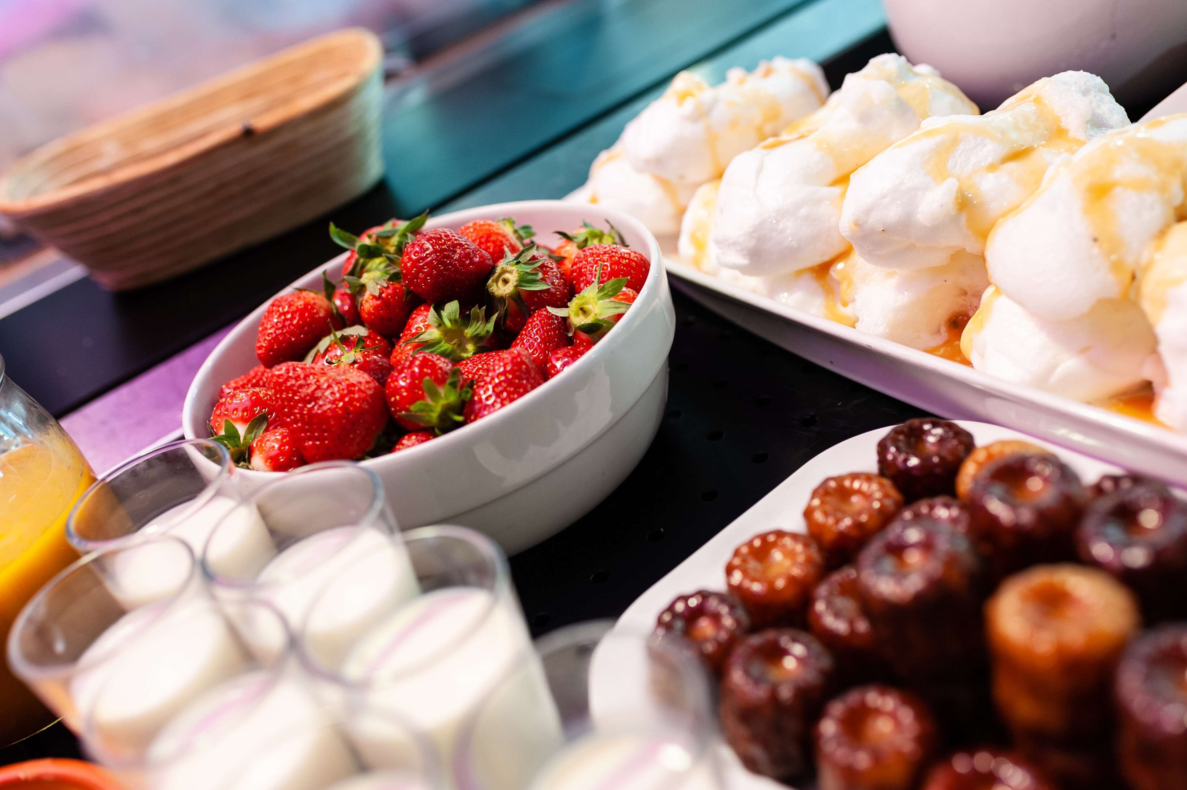 Un bufé con diversos alimentos, incluyendo fresas, malvaviscos y otros postres.