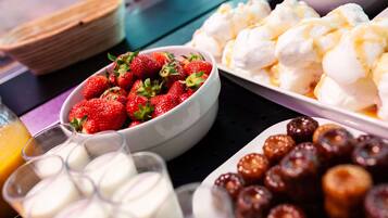 Un bufé con diversos alimentos, incluyendo fresas, malvaviscos y otros postres.