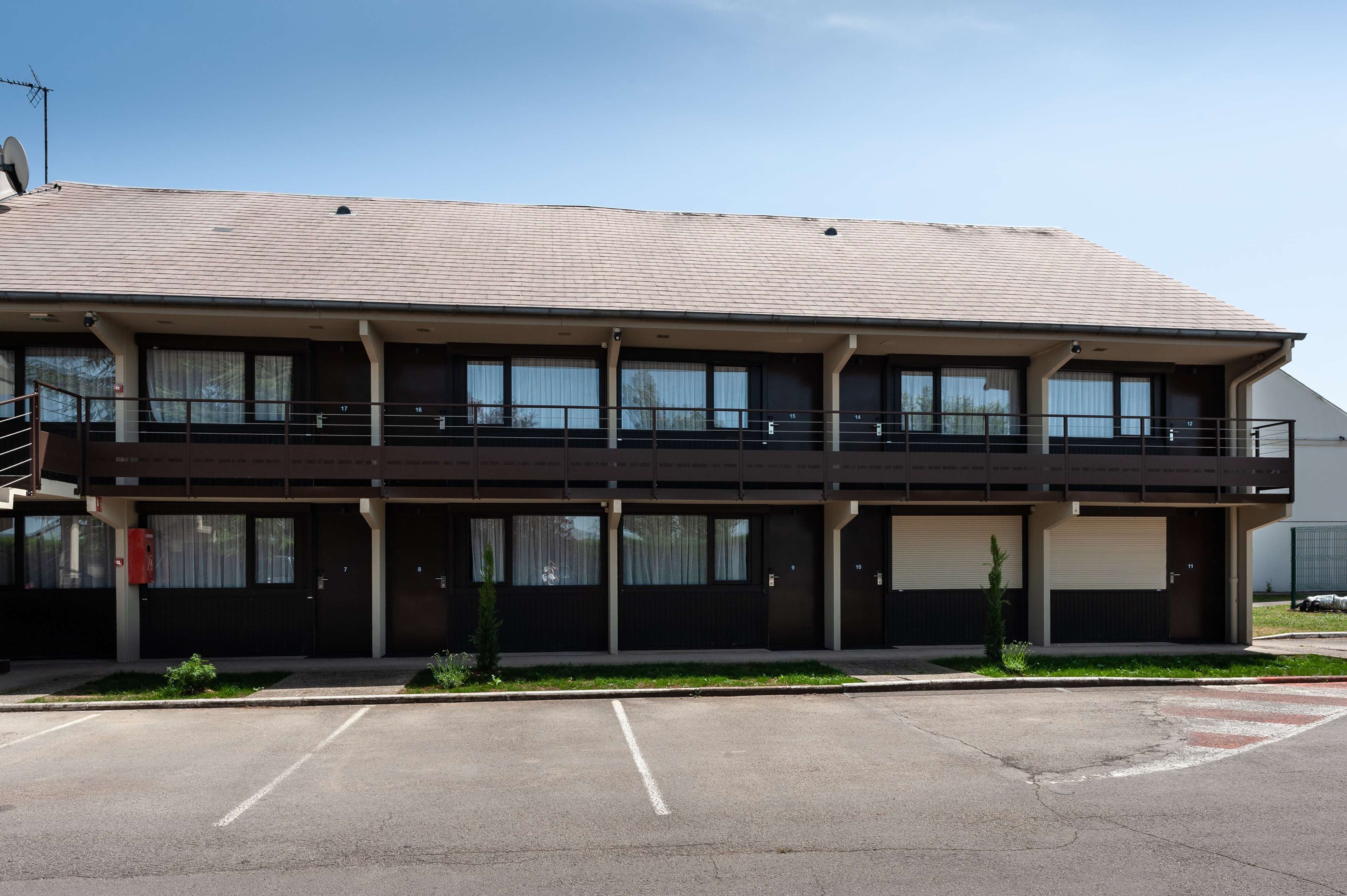 A two-story building with a flat roof, large windows, and a balcony on the second floor.