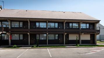 A two-story building with a flat roof, large windows, and a balcony on the second floor.