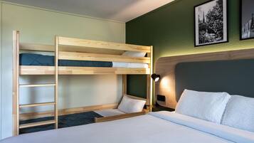 A bunk bed room with a ladder, a bedside table with a lamp, and two framed pictures on the wall.