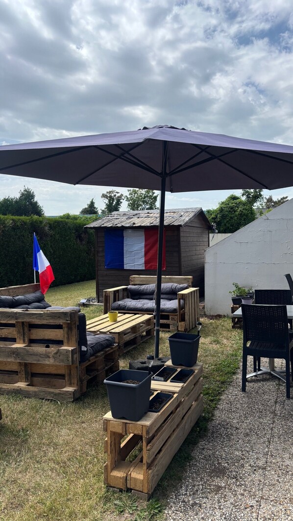 A rustic outdoor seating area with wooden furniture, a flag, and a small shed. - Hotel Campanile Conflans Sainte Honorine (Conflans-Sainte-Honorine)