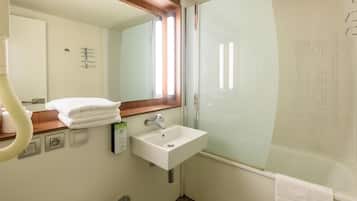 Une salle de bain avec un lavabo blanc, un miroir, un porte-serviettes et un espace douche.
