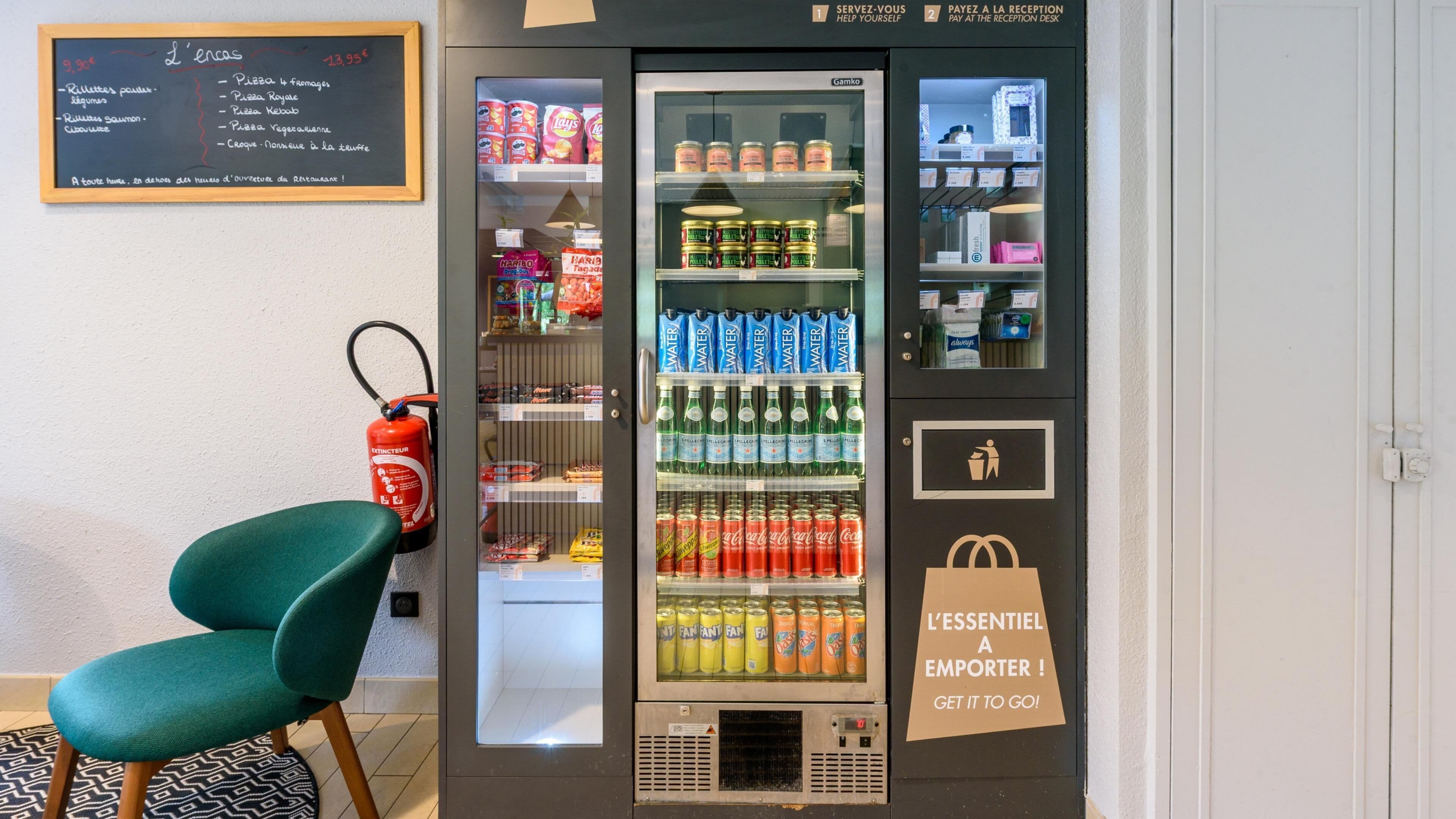 Een automaat met diverse dranken en snacks, een brandblusser, en een bord met een menu.