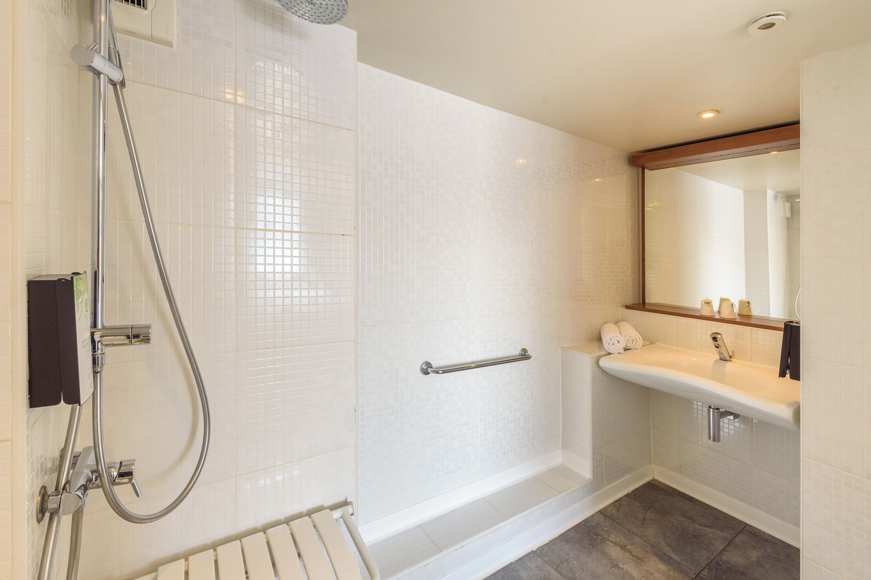 Une salle de bain moderne avec une douche à l’italienne, un meuble-lavabo avec un miroir et un porte-serviettes.