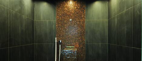 A modern shower area with a tiled wall, a handheld showerhead, and a bench.