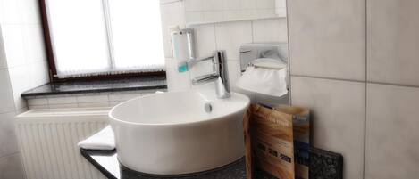 A bathroom with a white sink, a mirror, a towel rack, and a window.