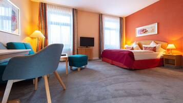 A hotel room with a bed, a desk, a chair, a television, and a window with curtains.