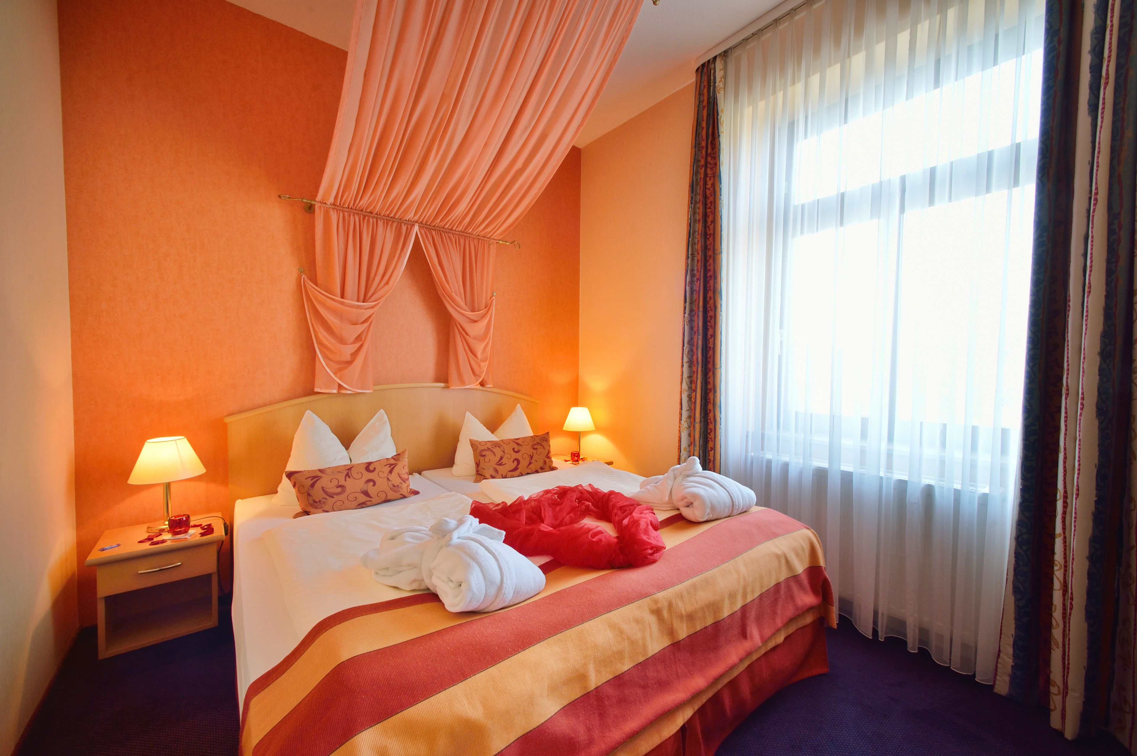 Ein Hotelzimmer mit einem Bett, zwei Nachttischlampen, einem Nachttisch und einem Fenster mit Vorhängen.