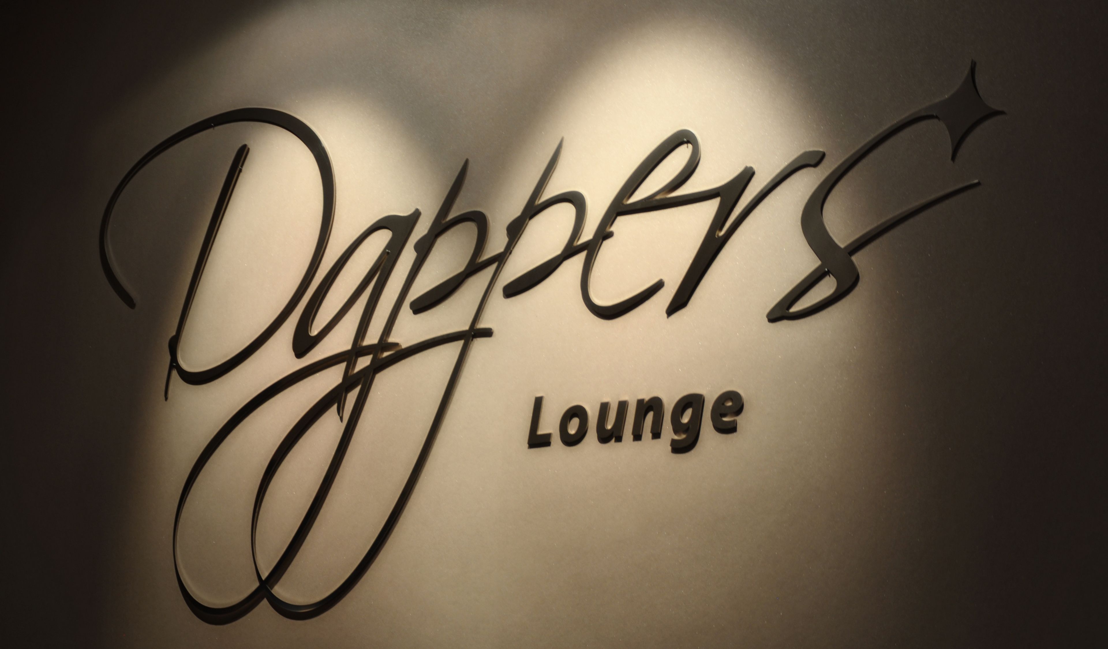 Una pared con el texto "Dapper Lounge" en letras estilizadas.
