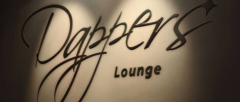 Una pared con el texto "Dapper Lounge" en letras estilizadas.