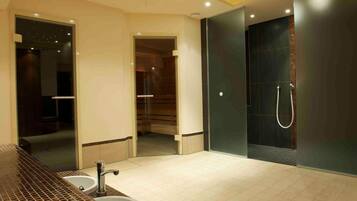 A modern bathroom with a large mirror, two sinks, a shower, and a walk-in closet.