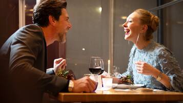 A dining table with a wine glass, a cup, and a plate of food.