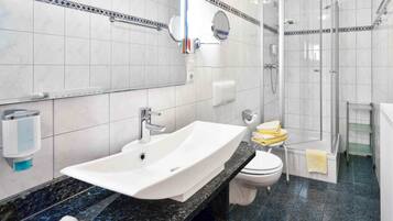 A bathroom with a white sink, toilet, and shower.