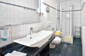 A bathroom with a white sink, toilet, and shower. - Dappers Hotel - Spa - Genuss (Bad Kissingen)